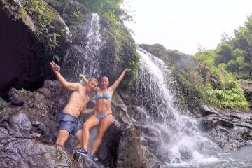 A couple smiling on the rocks near the jungle waterfall